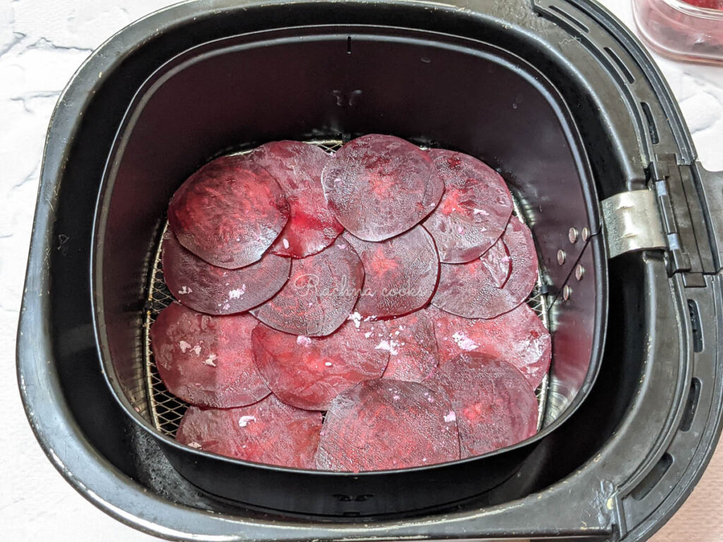 Beetroot slices spread out in air fryer basket.