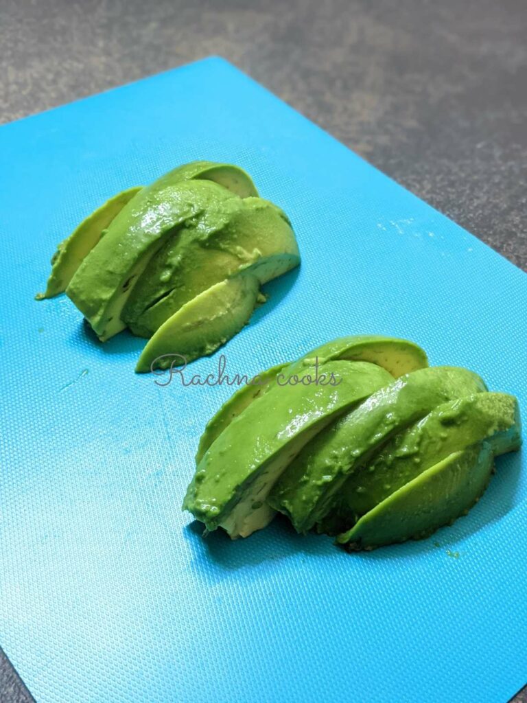 One avocado cut into slices or fries on a blue surface