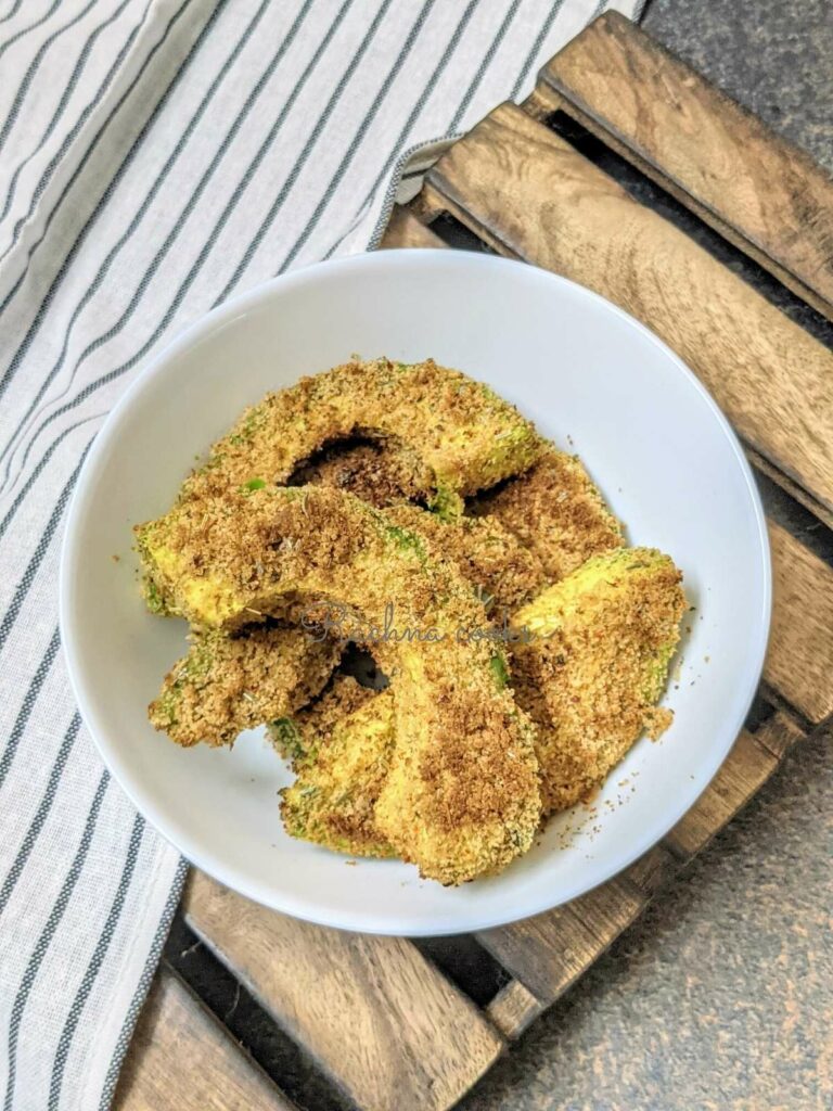 air fried avocado fries in a white bowl with a wooden tray in background.