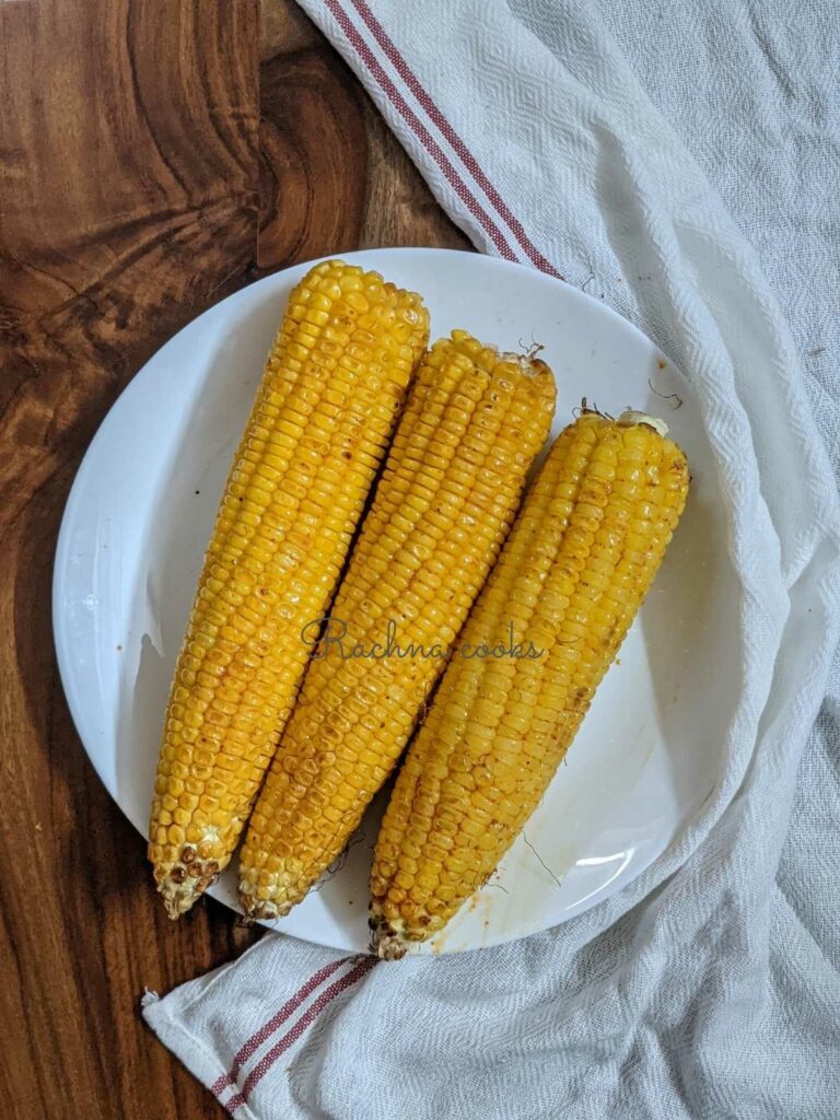 3 corn on the cob air fried and kept on a white plate.