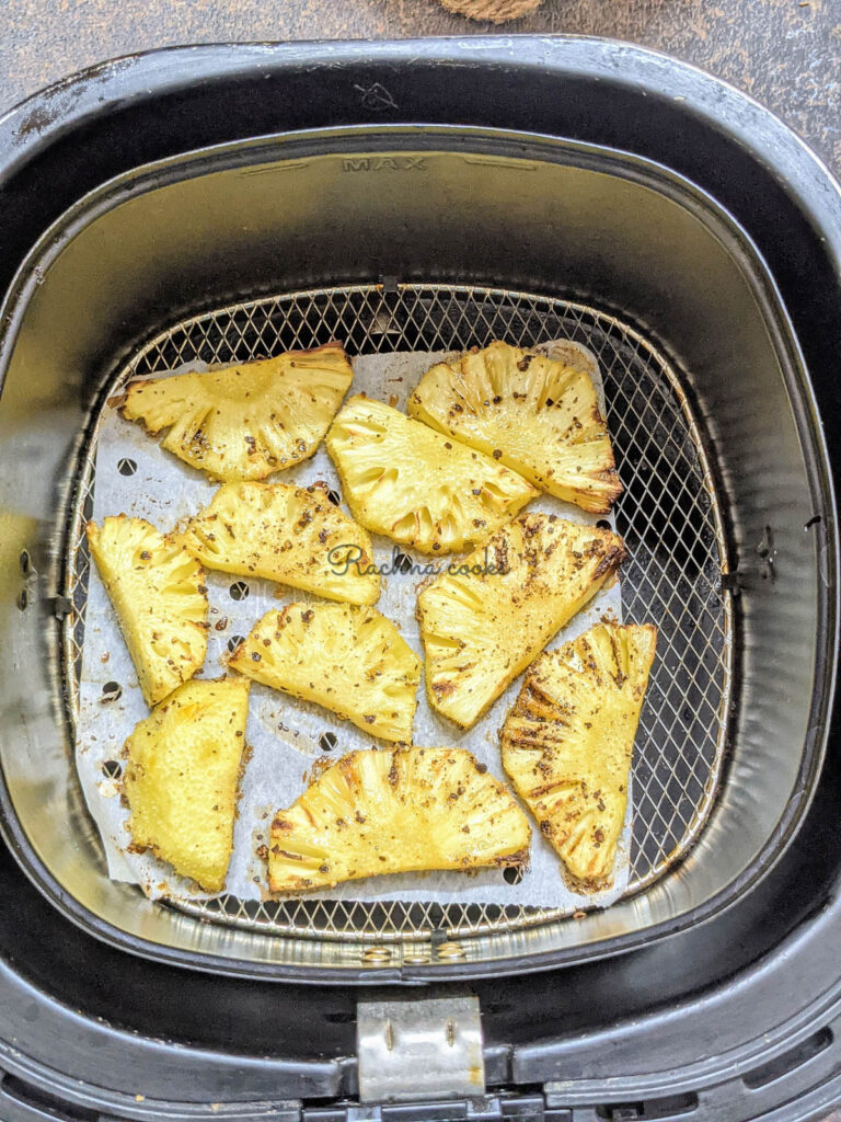 Roasted pineapple slices after air frying in air fryer basket.