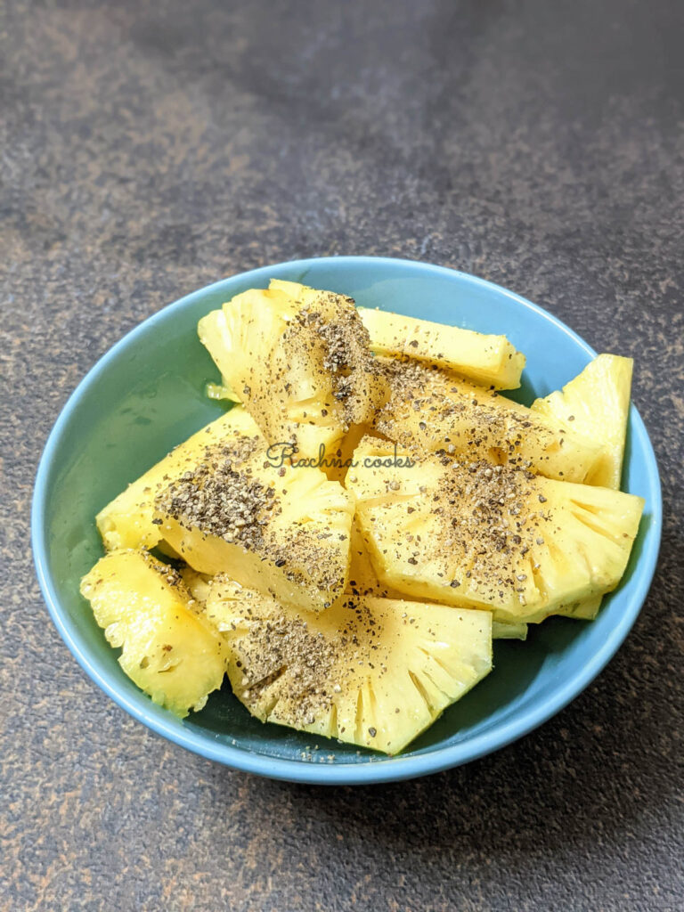 Pineapple slices marinated with honey and ground pepper in a blue bowl