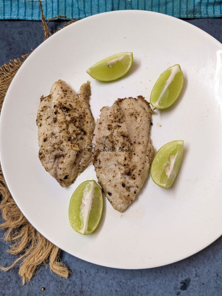 Air fryer tilapia fillets with lemon wedges on a white plate