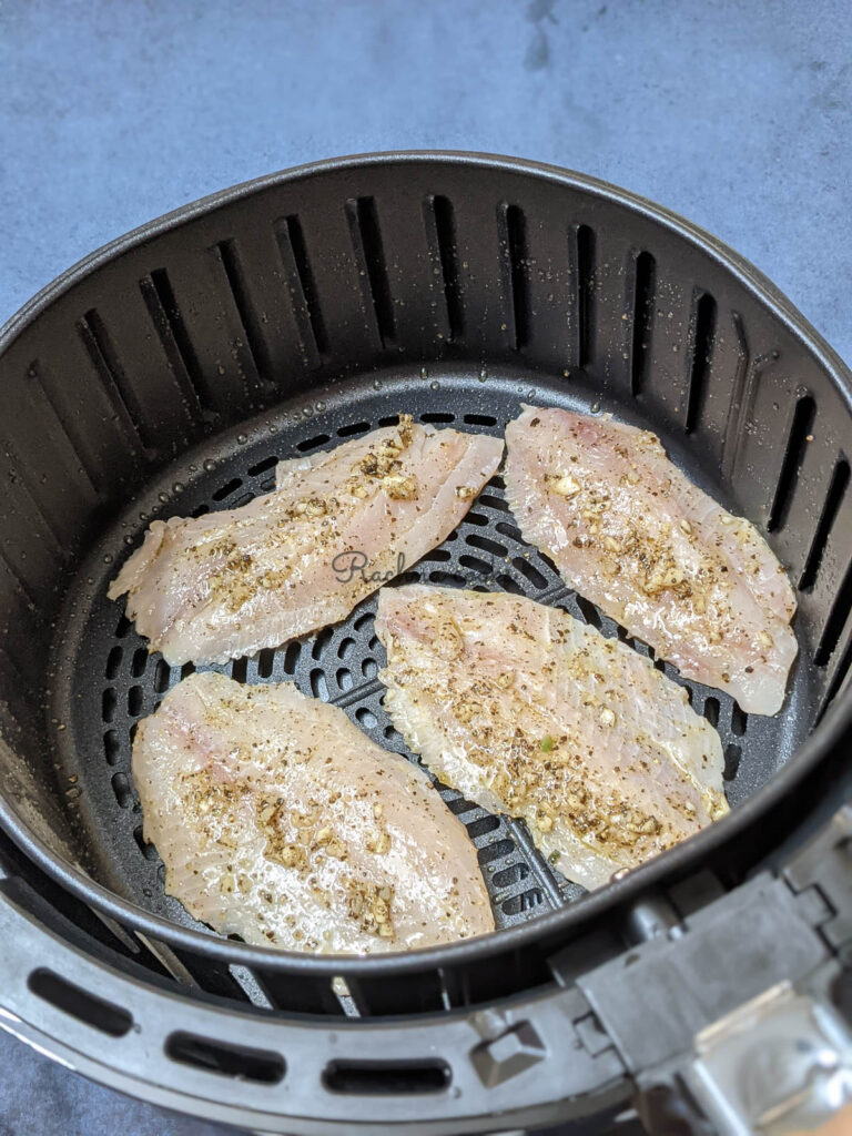 Tilapia fillets in air fryer basket ready for air frying