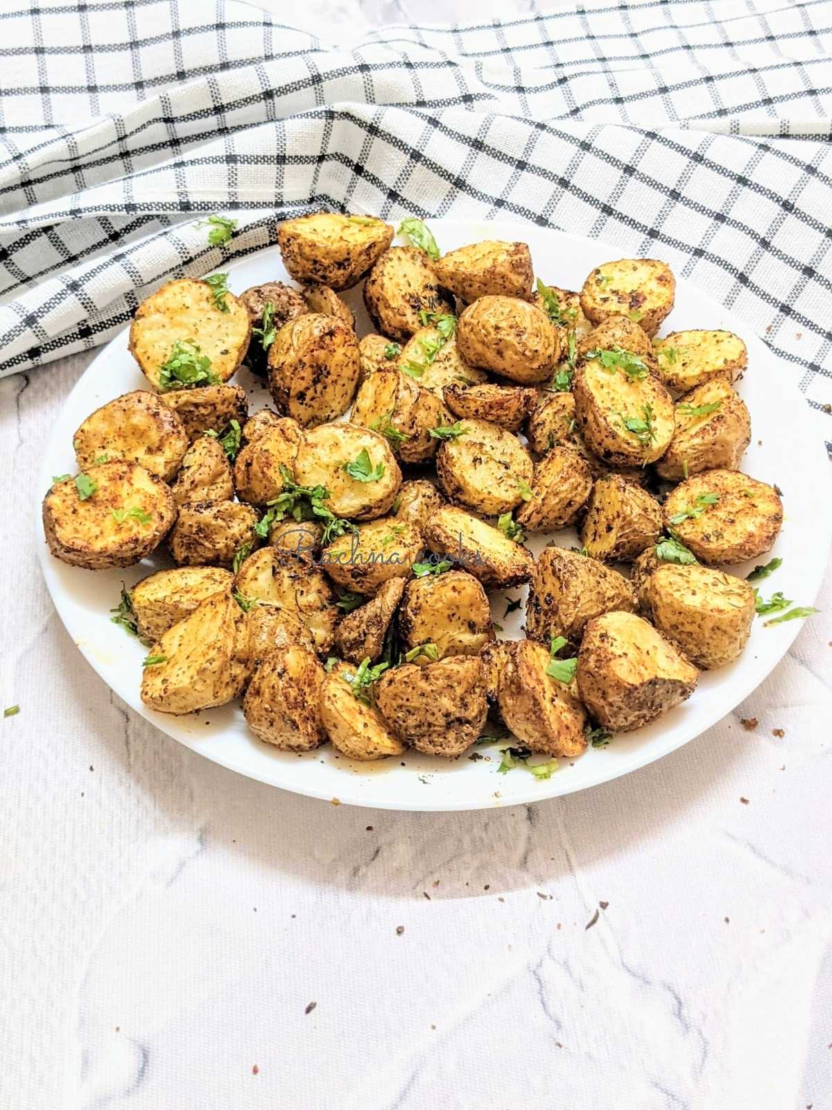 A plate of roasted baby potatoes with a check napkin in background.