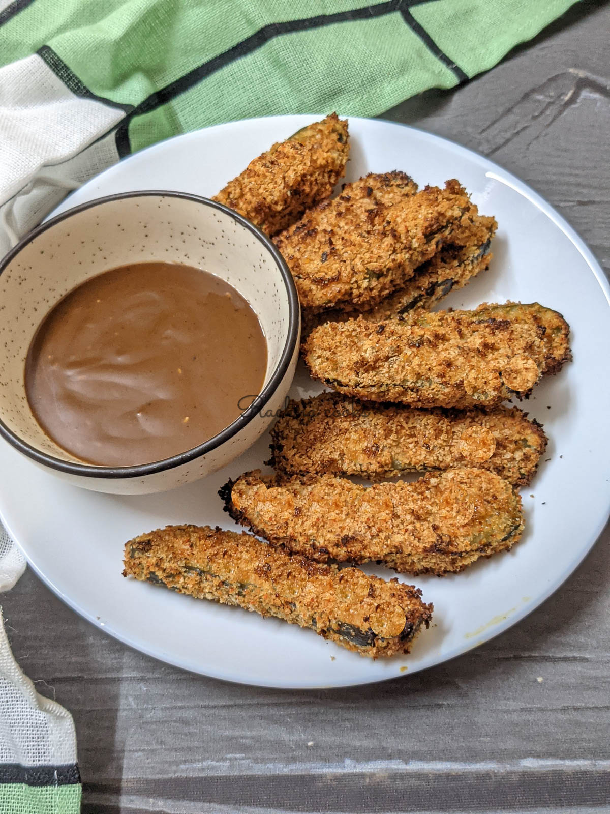 A plate of air fried pickles served with a dip