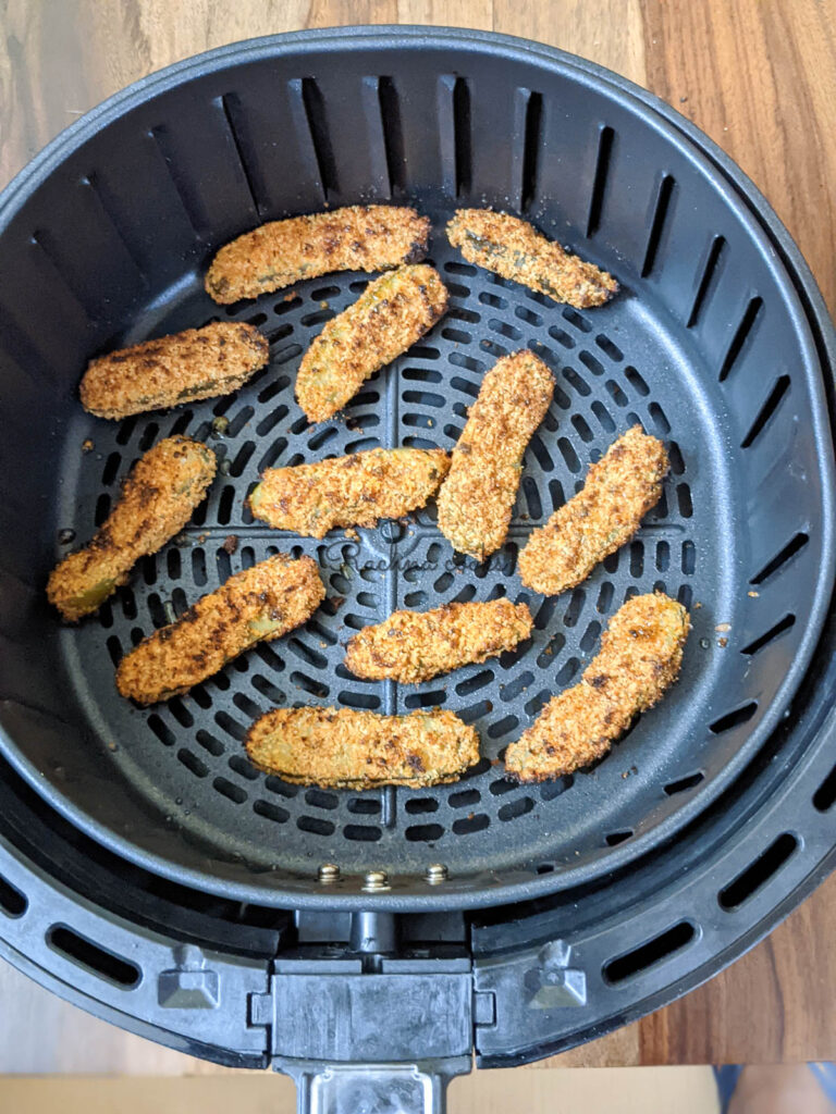 Golden fried air fried pickle slices in air fryer basket.