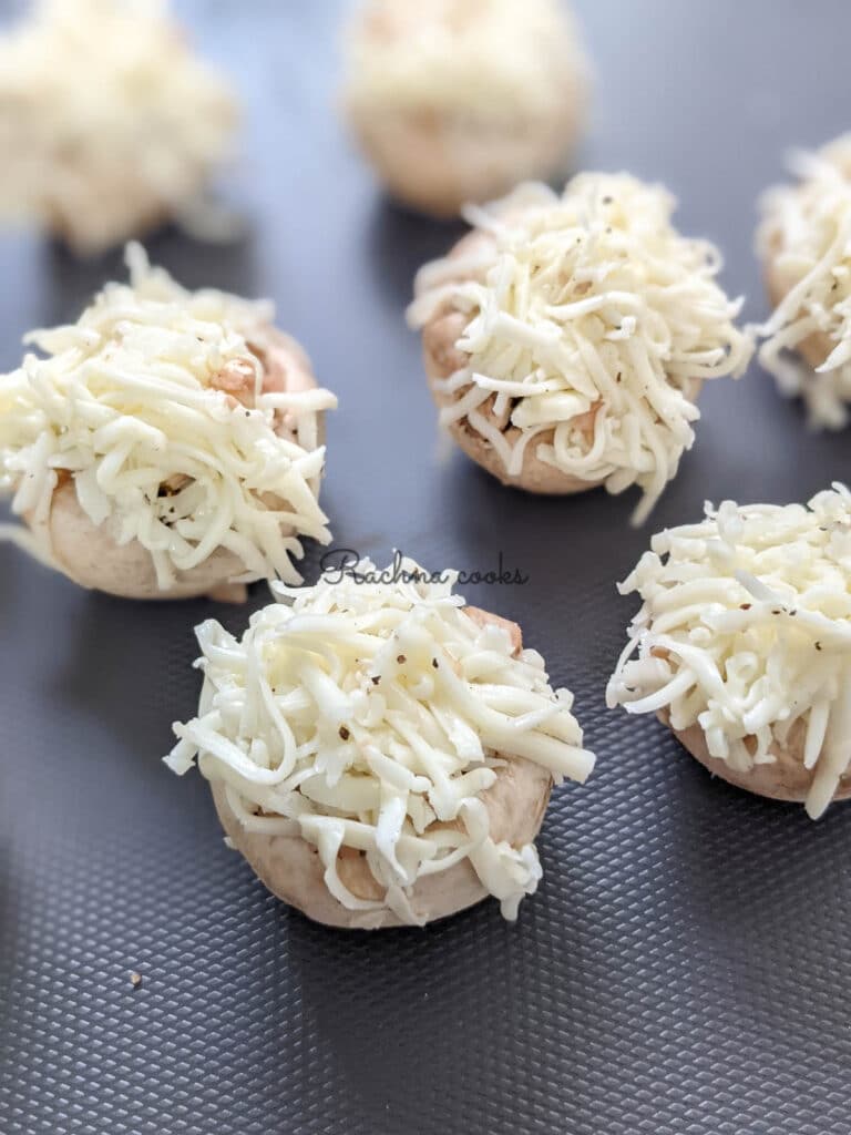 Mushroom caps stuffed and garnished with grated cheese ready for air frying.