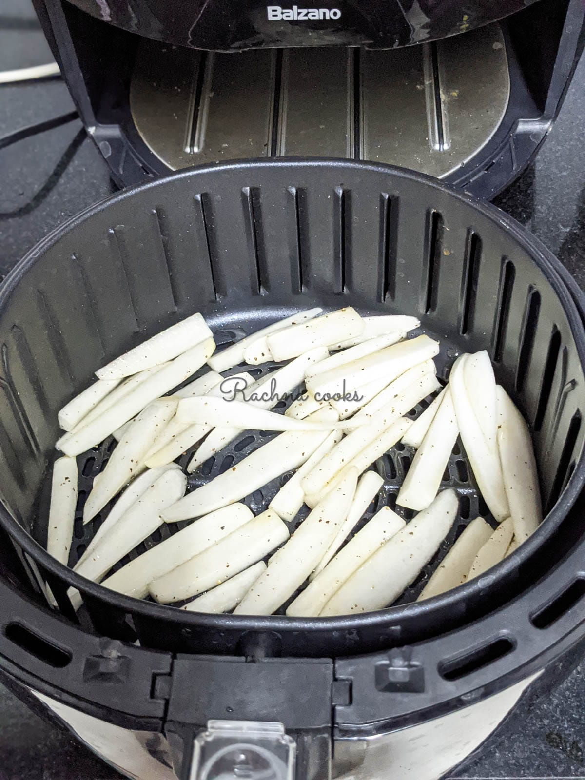 Air fryer basket with one layer of parsnip fries in it ready for air frying.
