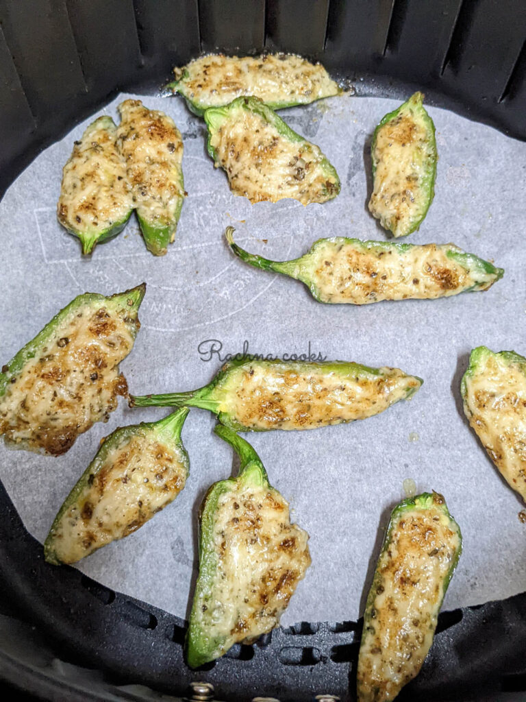 Golden air fried jalapeno poppers on a parchment paper lined air fryer basket
