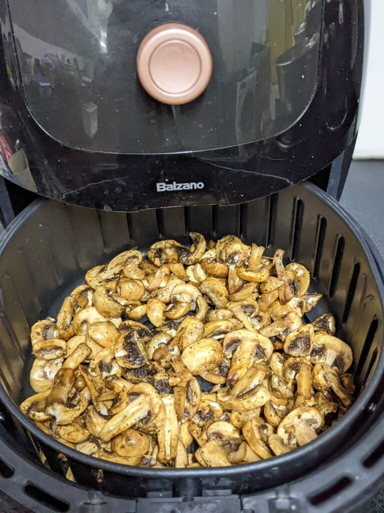 Marinated mushroom slices in air fryer basket for air frying.