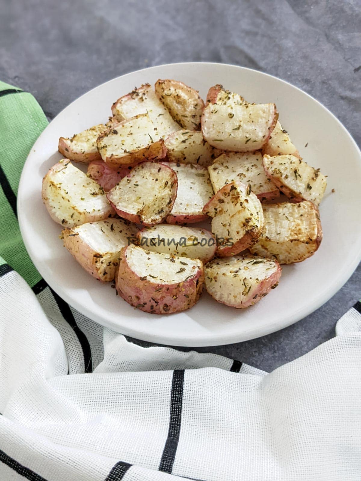 Delicious air fried roasted radishes with crispy outside and soft cooked inside. Halved or quartered pieces on a white plate.