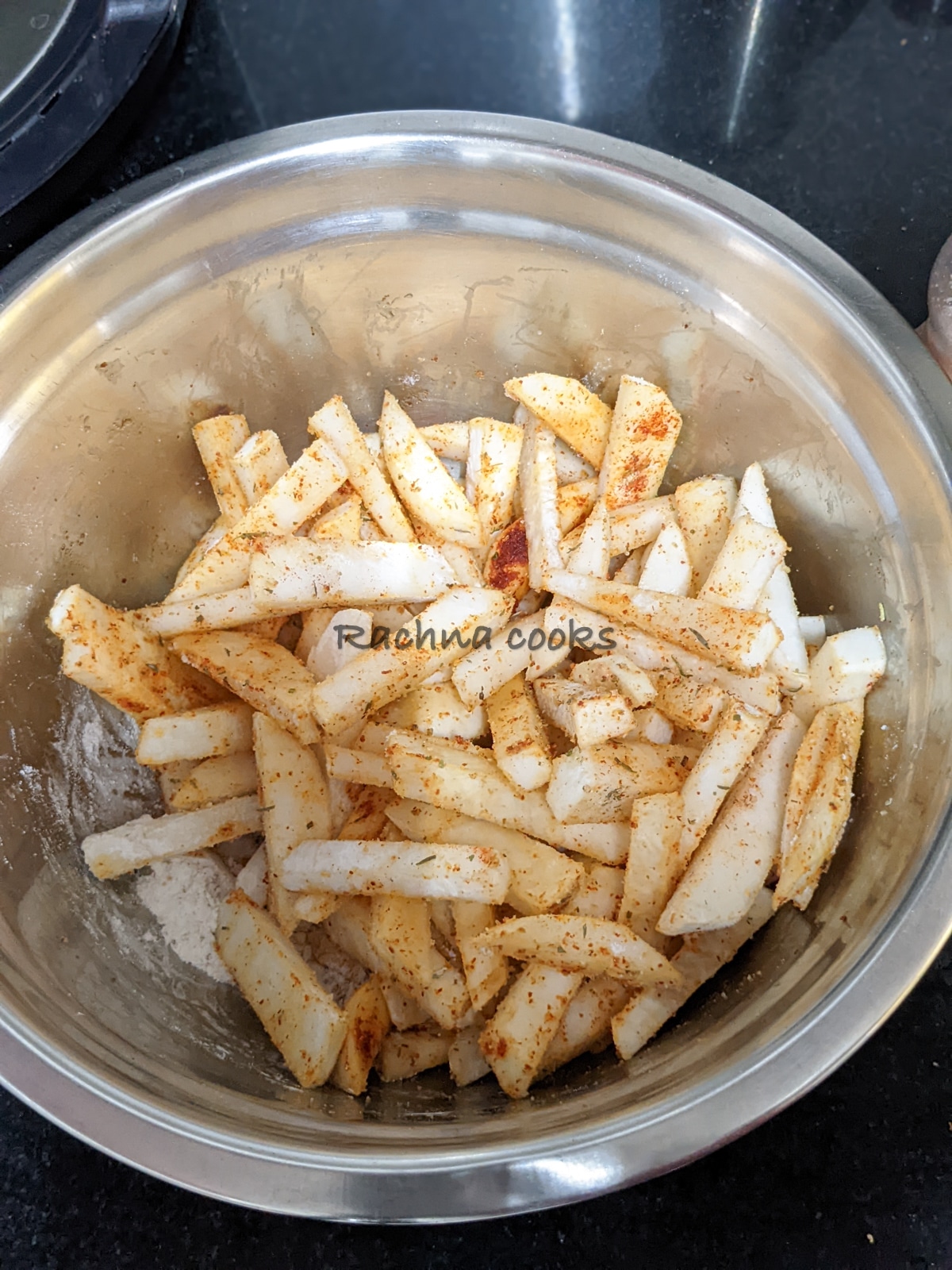 Turnip fries in a steel bowl tossed with seasonings.