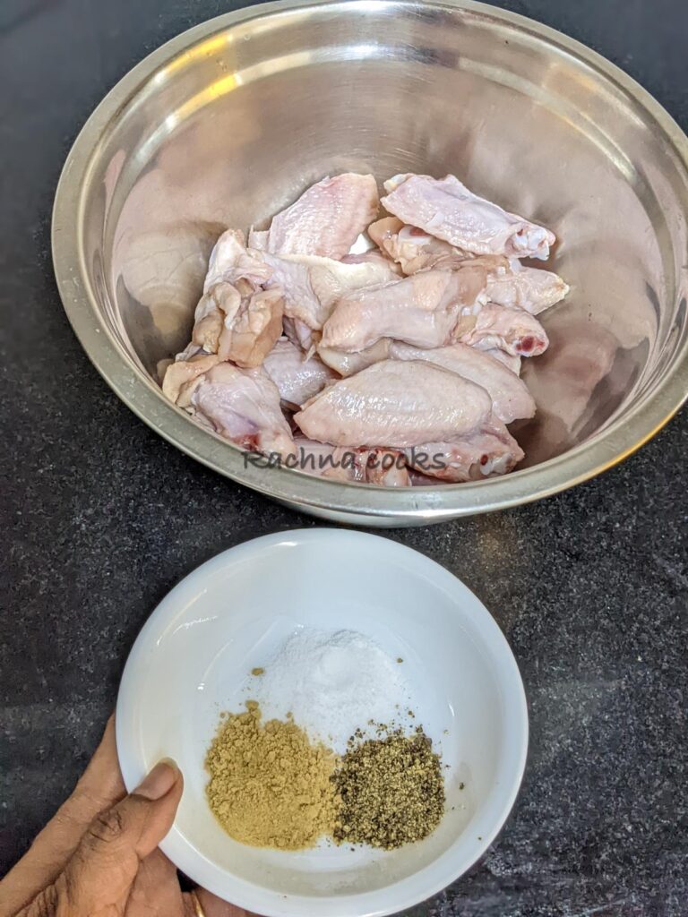 Chicken wings patted dry in a bowl along with salt, pepper and garlic powder in another bowl.