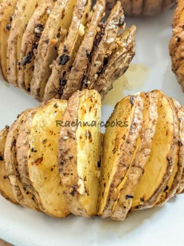 Close up of 2 air fried hasselback potatoes on a white plate