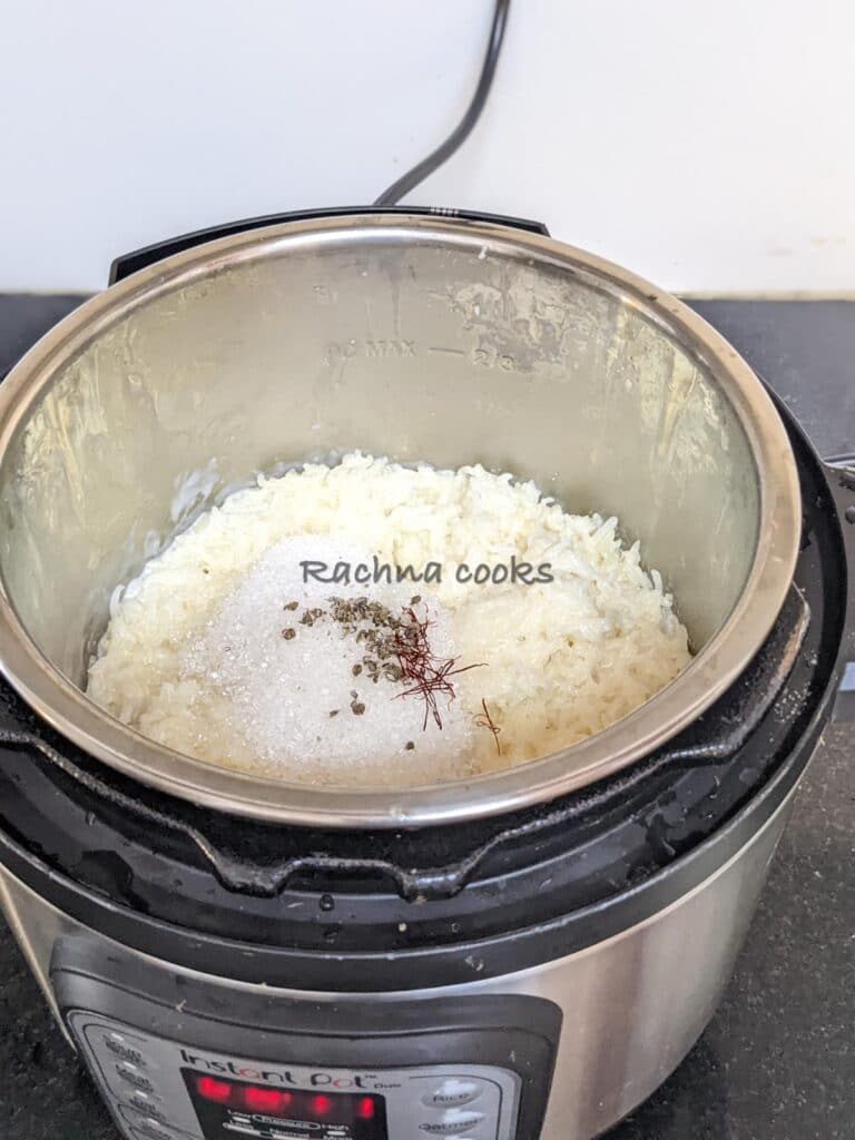Instant pot with cooked rice with milk after adding sugar, saffron strands and cardamom powder.