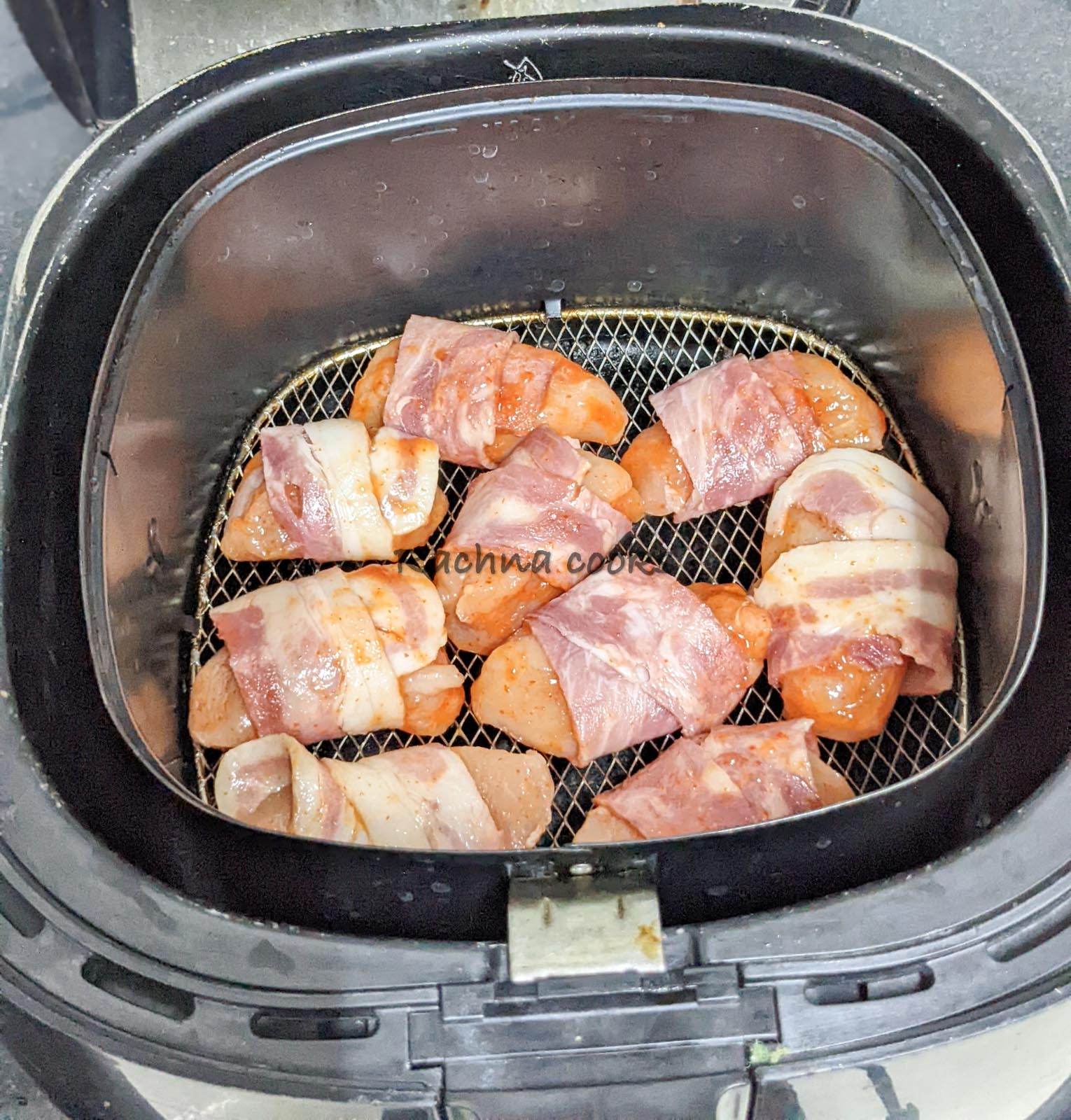 Bacon wrapped chicken bites placed in air fryer basket ready for air frying.