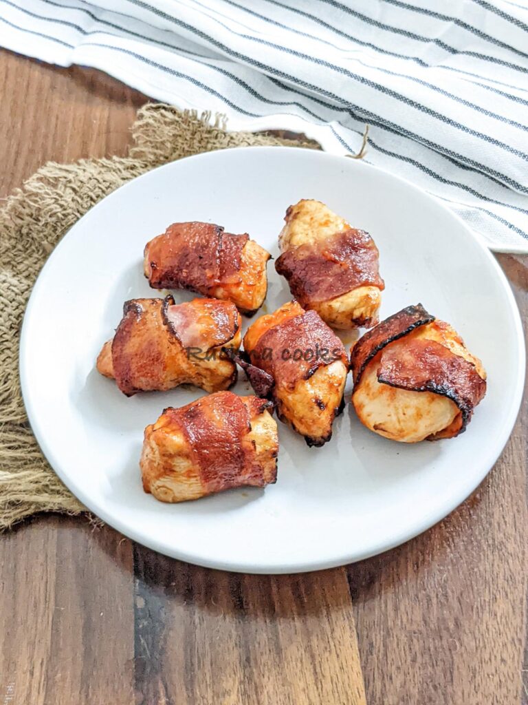 6 air fried bacon wrapped chicken bites on a white plate.