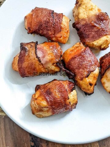 Bacon wrapped chicken bites on a white plate.