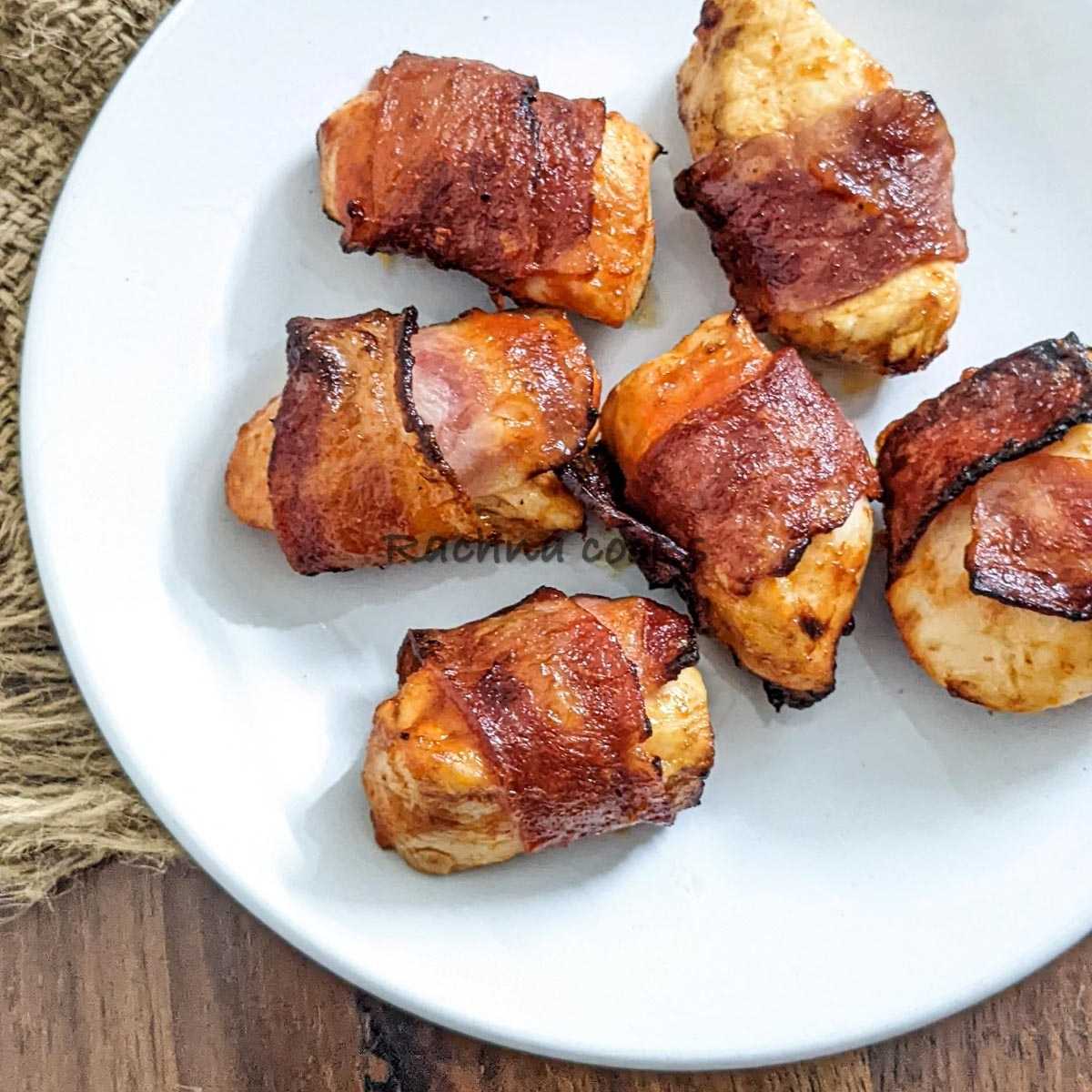 Bacon wrapped chicken bites on a white plate.