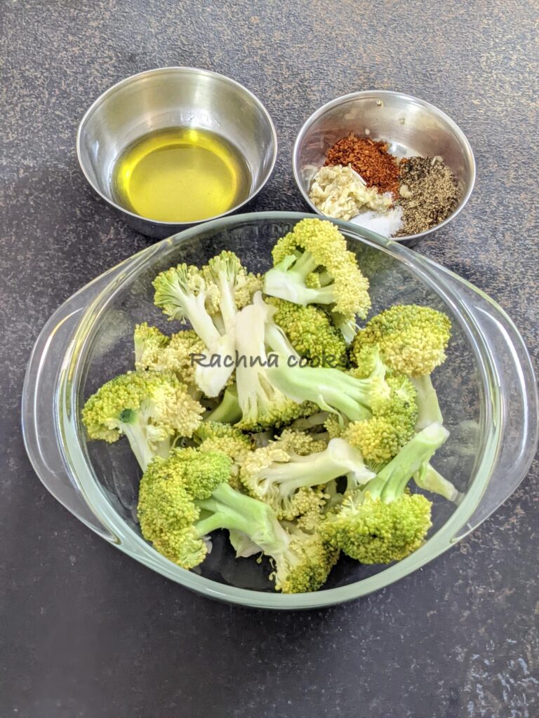 A bowl of broccoli florets with a bowl of olive oil and seasonings in another bowl.