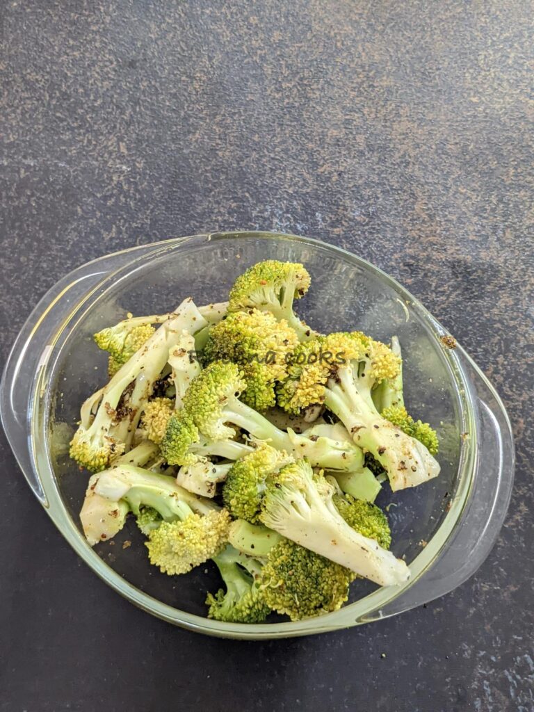 Broccoli florets in a bowl tossed with olive oil and seasonings.