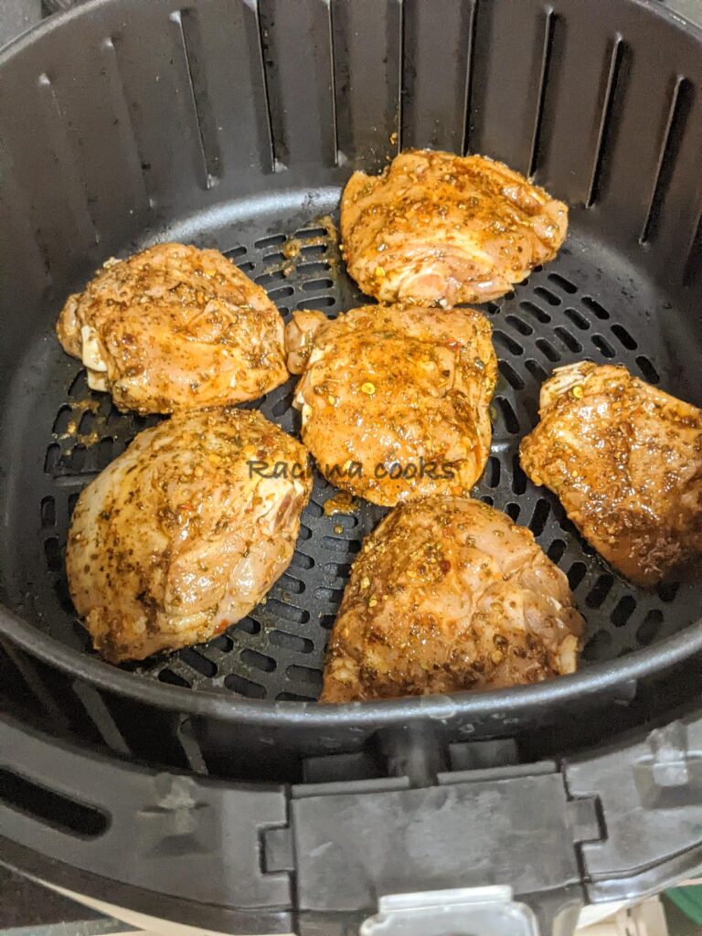 6 chicken thighs marinated and laid in air fryer basket for cooking.