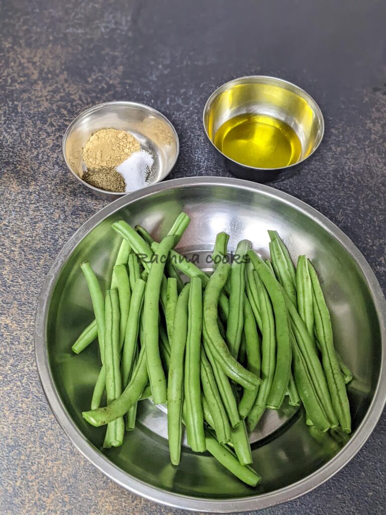 Green beans with snipped ends in a shallow plate. Olive oil in a bowl and garlic powder, salt and pepper in another bowl.