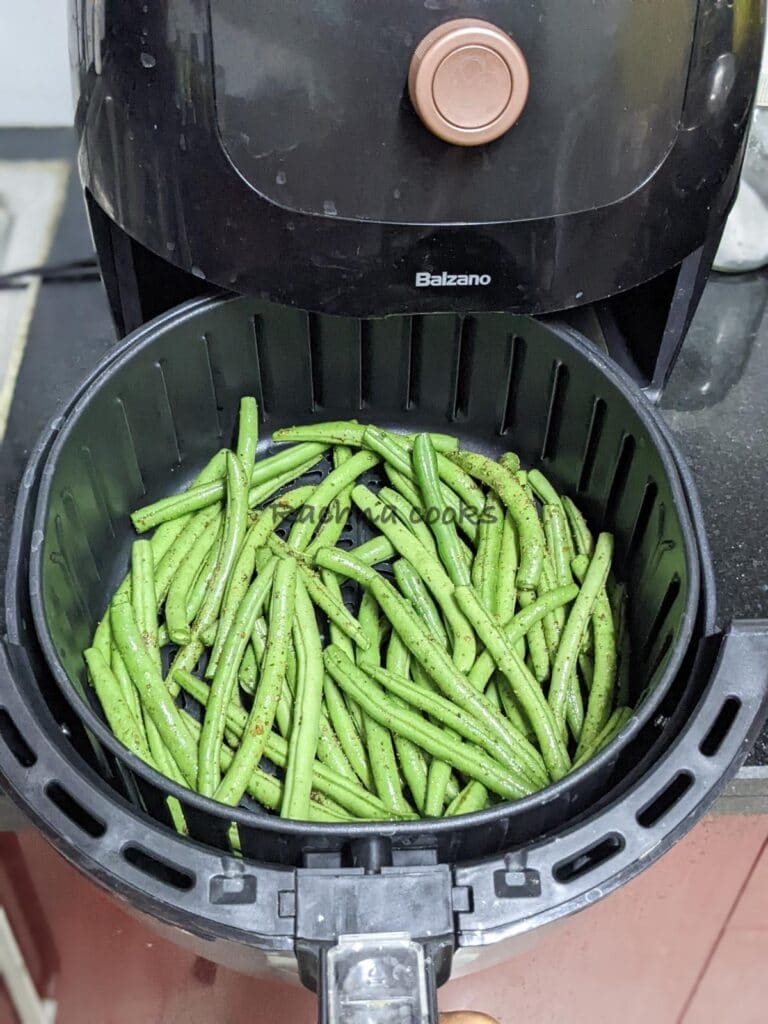 Green beans in air fryer basket ready for cooking.