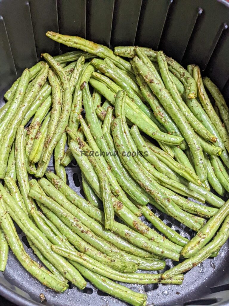 Close up of green beans in air fryer basket after cooking