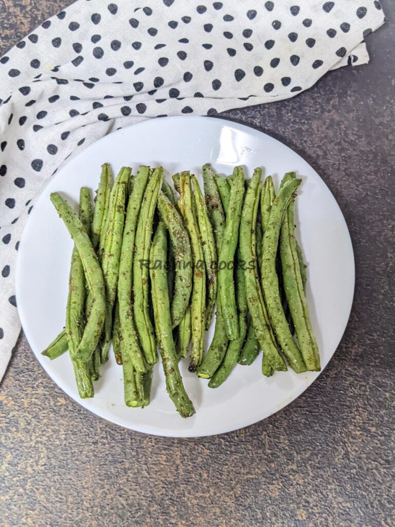 Top shot of air fryer green beans on a white plate after air frying.