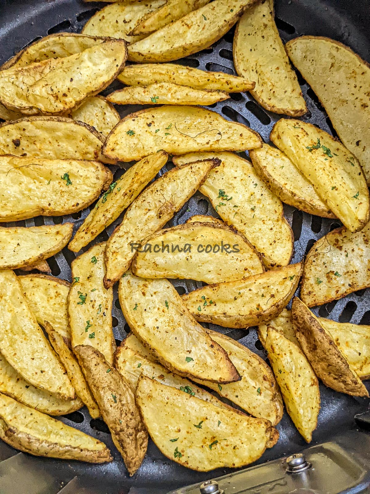 Top close up shot of crispy potato wedges in air fryer basket.