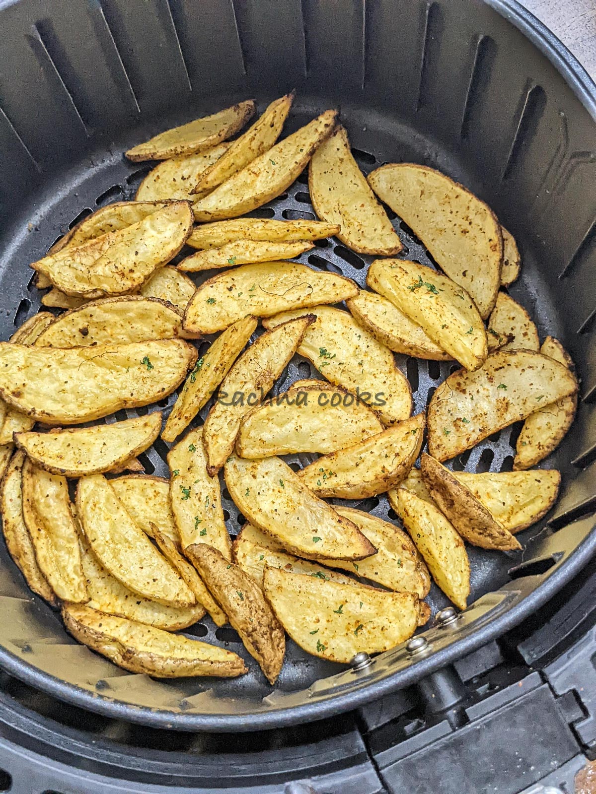 Crispy Potato wedges after air frying in air fryer basket.