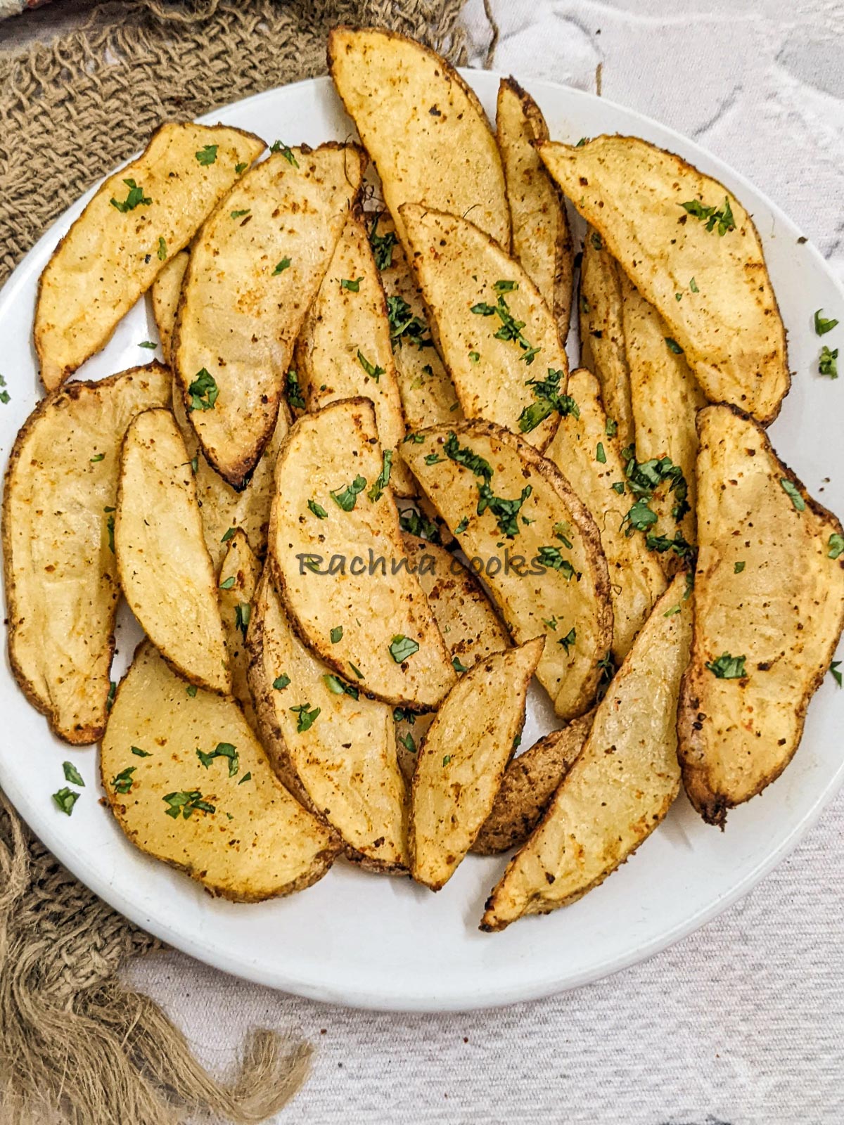 Top close up shot of crispy potato wedges on a white plate.