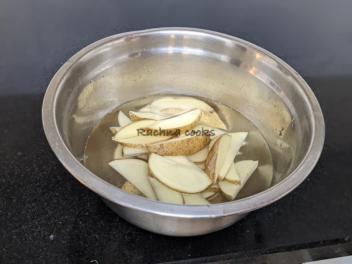 Cut potato wedges soaked in water in a steel bowl.