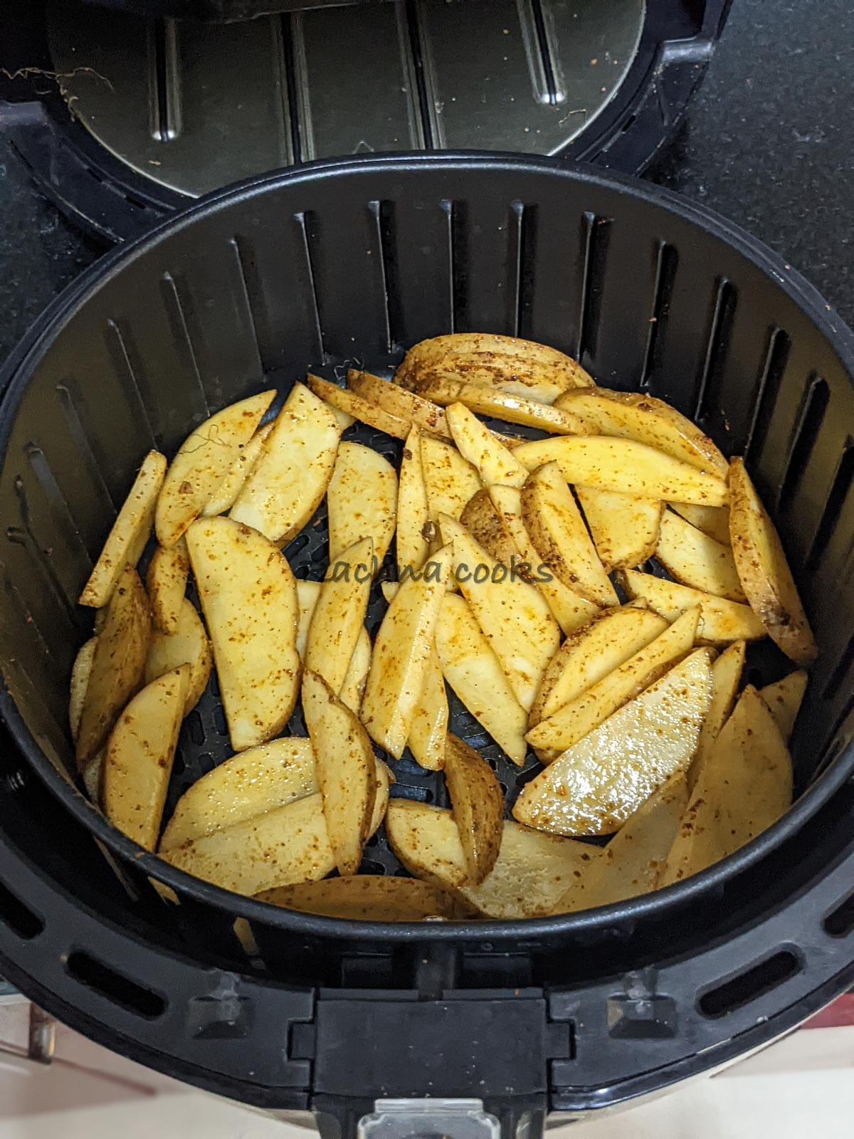 Seasoned potato wedges placed in one layer in air fryer basket.