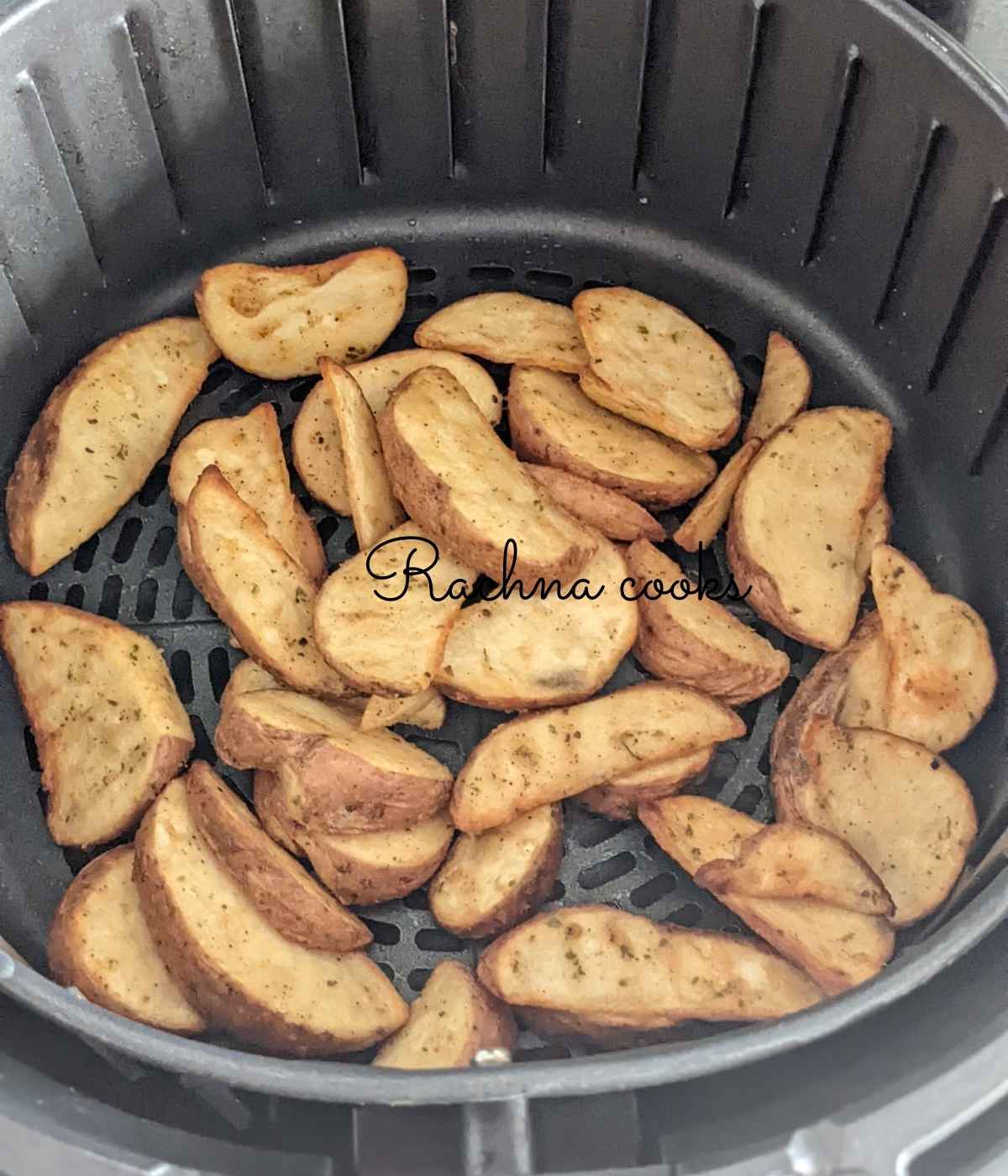 Frozen potato wedges in air fryer basket.