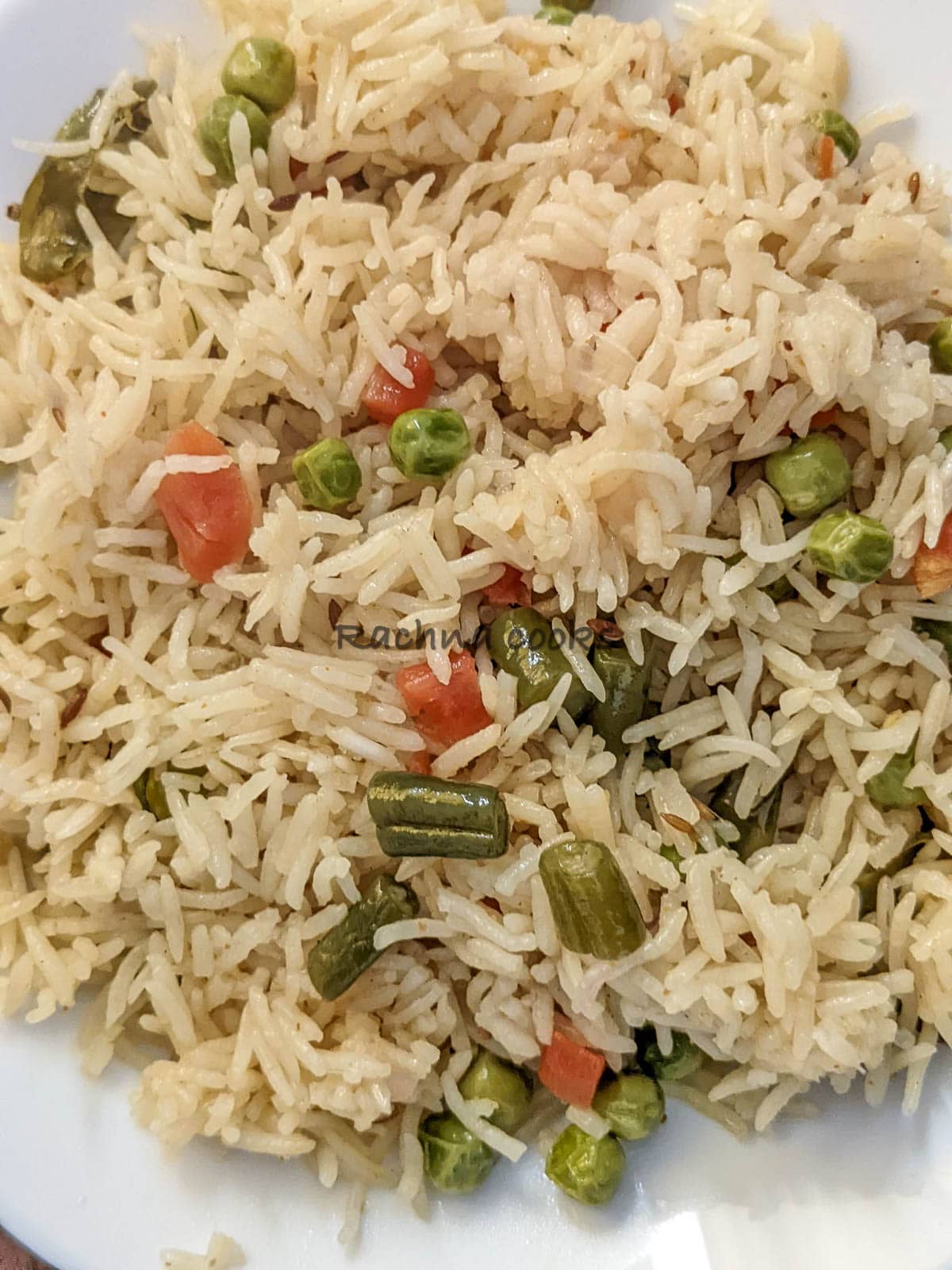 A close up of vegetable pulao on a white plate.