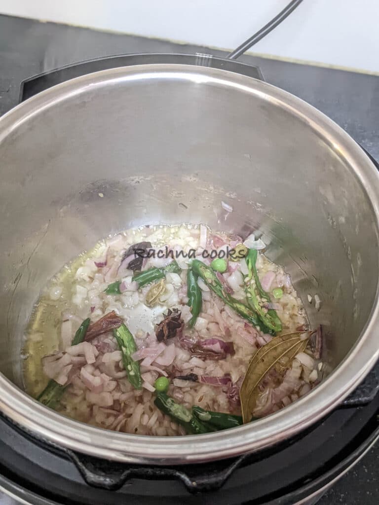 Onions and sliced green chillies being sauteed in instant pot.