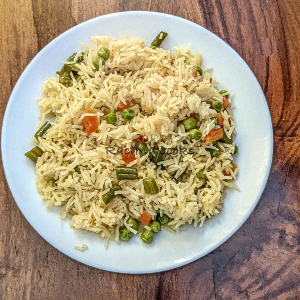 Top shot of vegetable pulao served in a white plate.