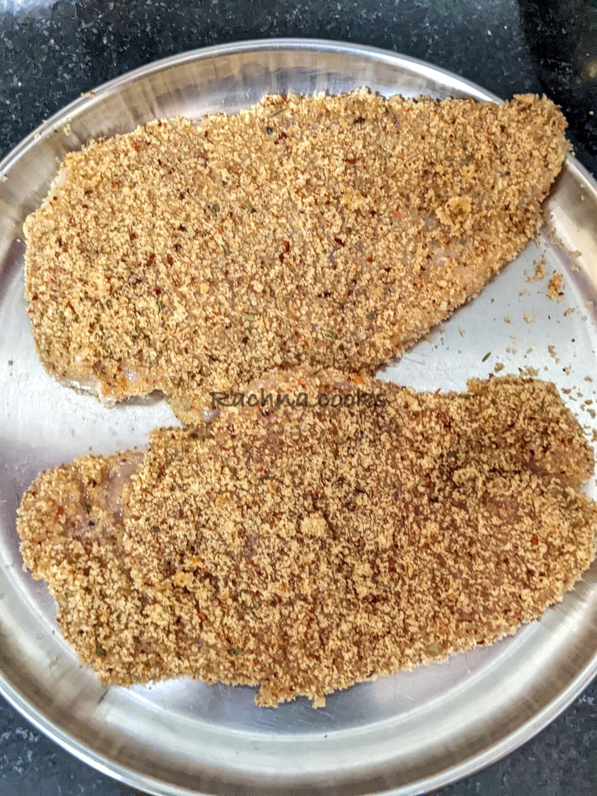 Two chicken breast slices after breading in a plate ready for air frying.