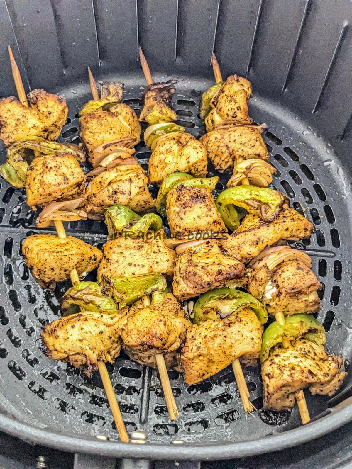 4 skewers of chicken kabob after air frying in air fryer basket.