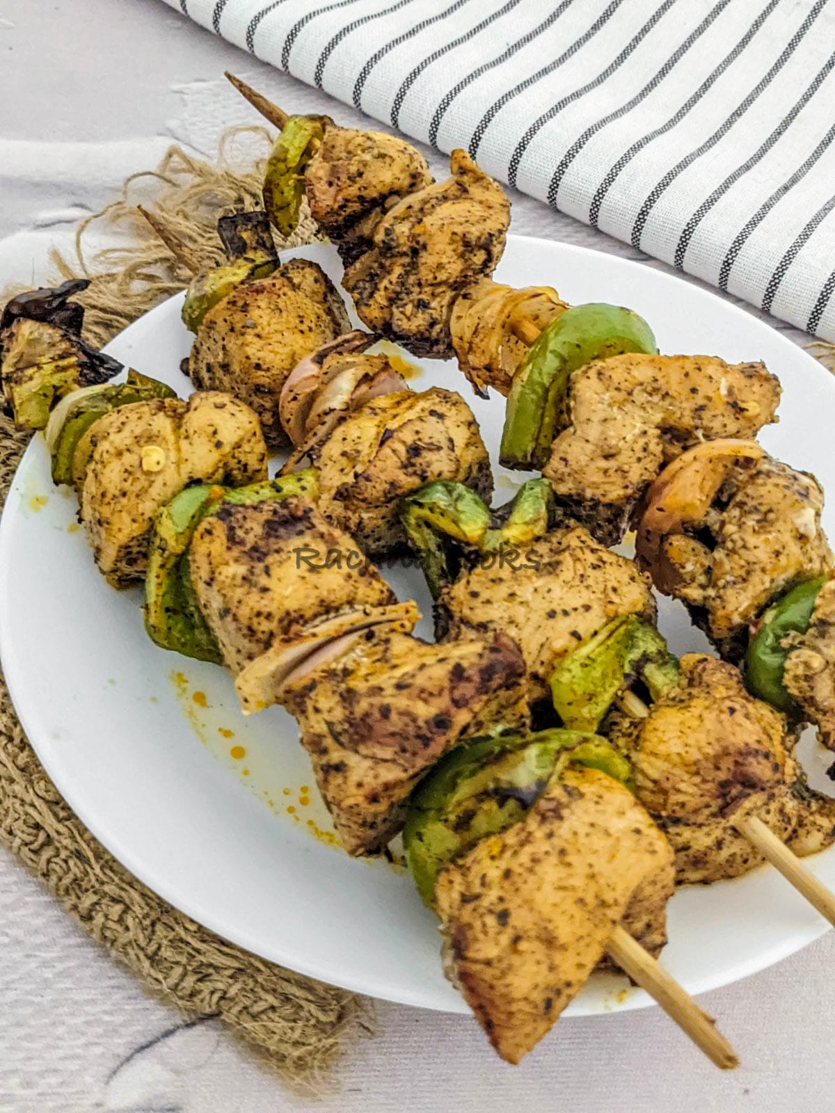 3 skewers of chicken kabob after air frying in a white plate.
