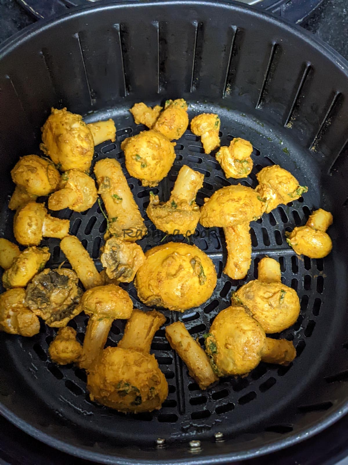 Marinated mushrooms in air fryer basket ready for air frying.