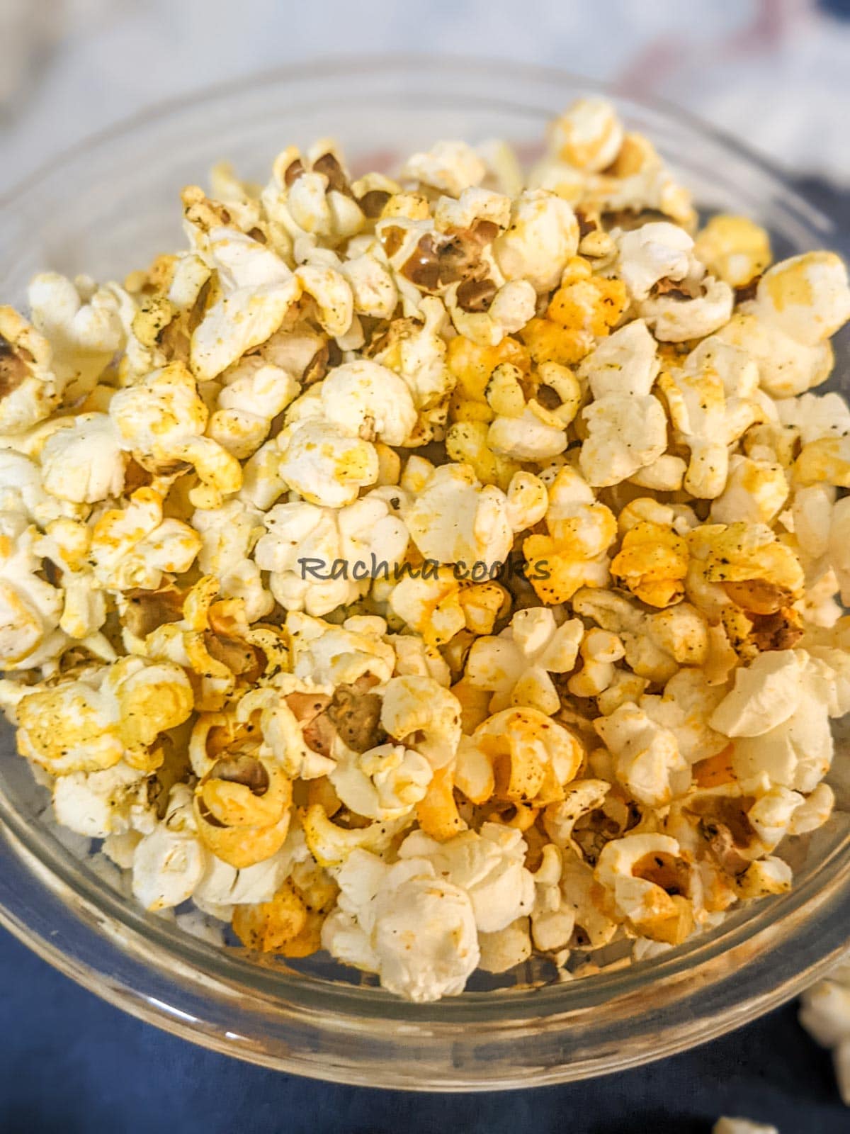 Top shot of popcorn in a glass bowl with a blue background