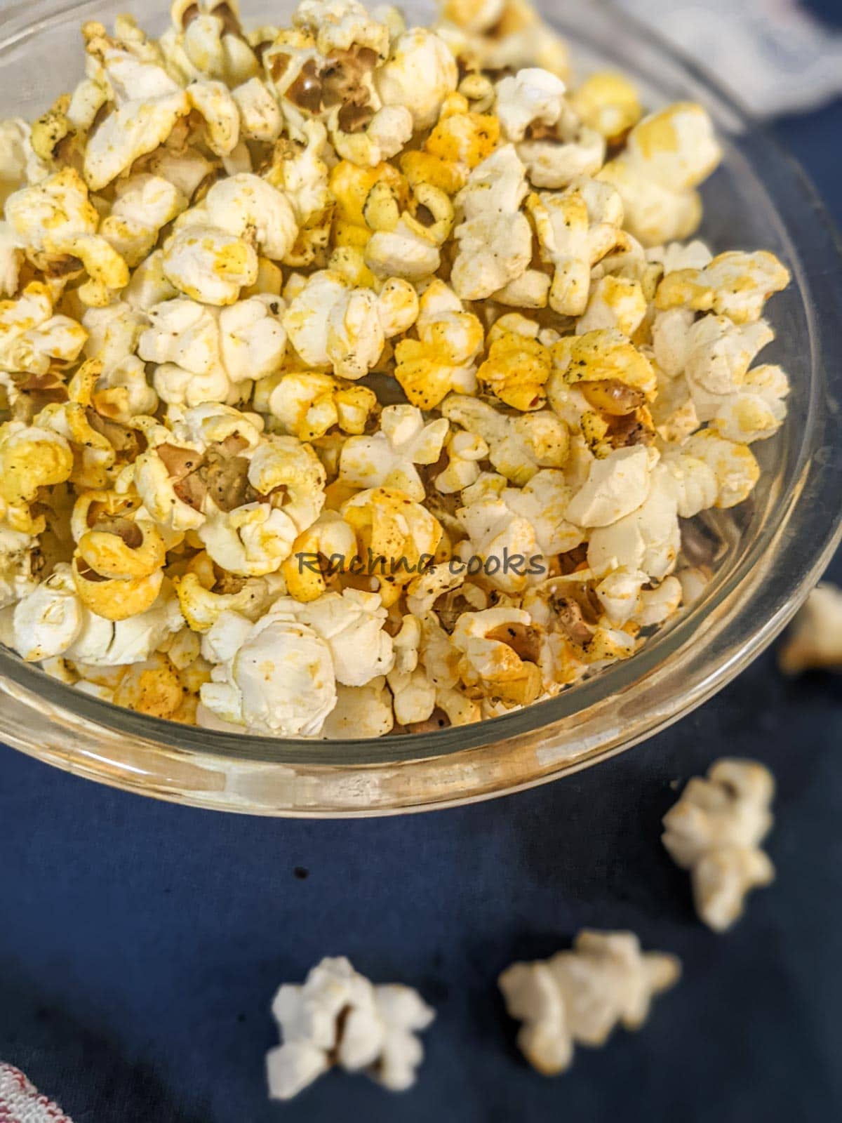 top and close up shot of popcorn in a glass bowl with a blue background