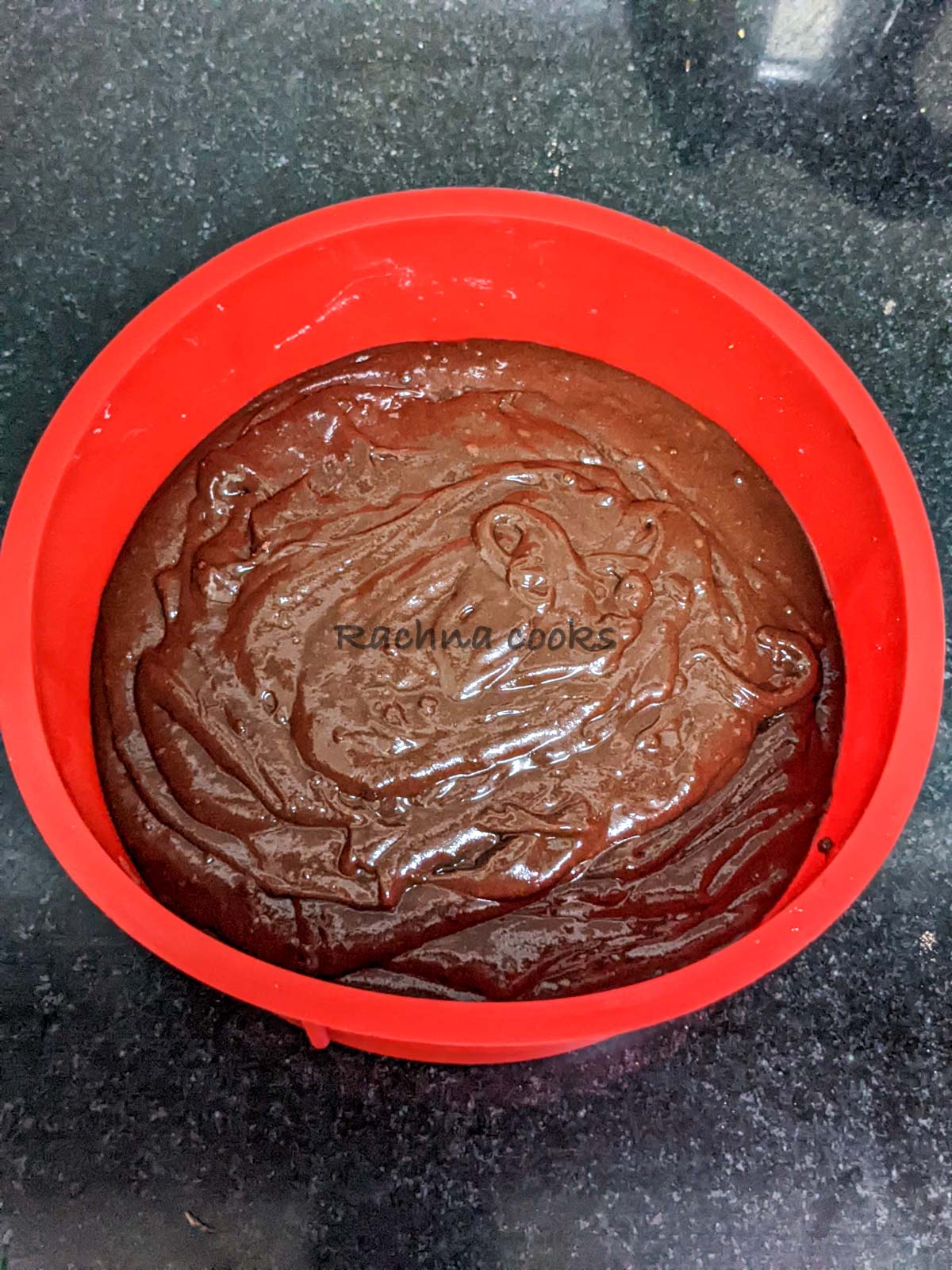 Cake batter poured into a red silicone cake mould.