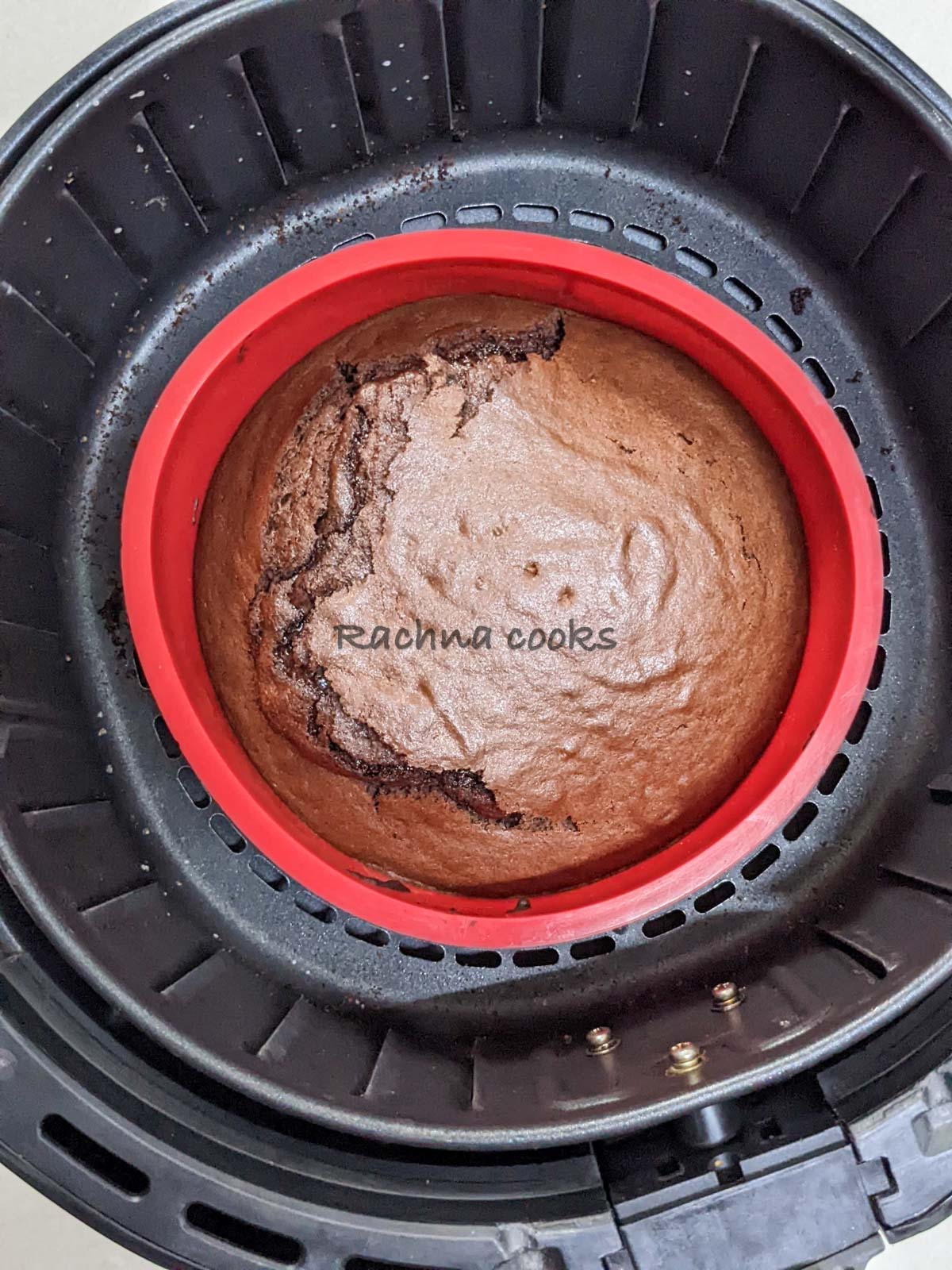 Chocolate cake after air frying in a red cake mould in air fryer basket.