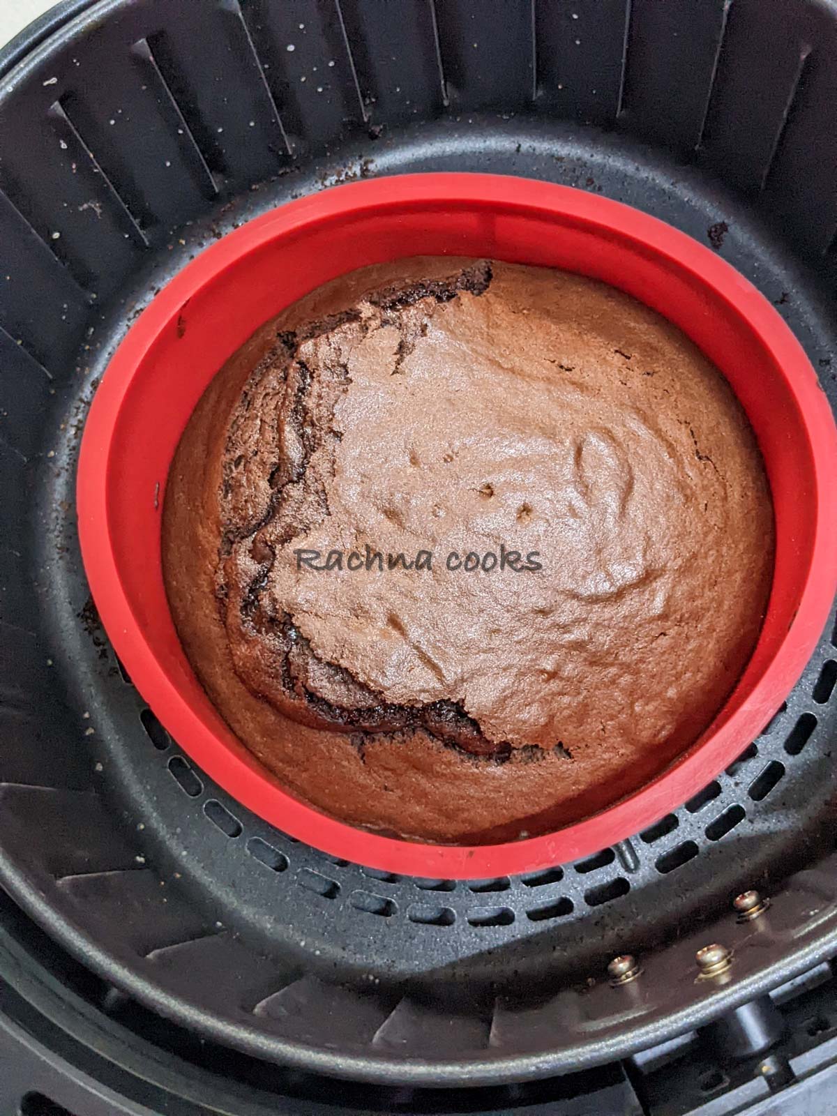 Chocolate cake in a red mould in air fryer basket.