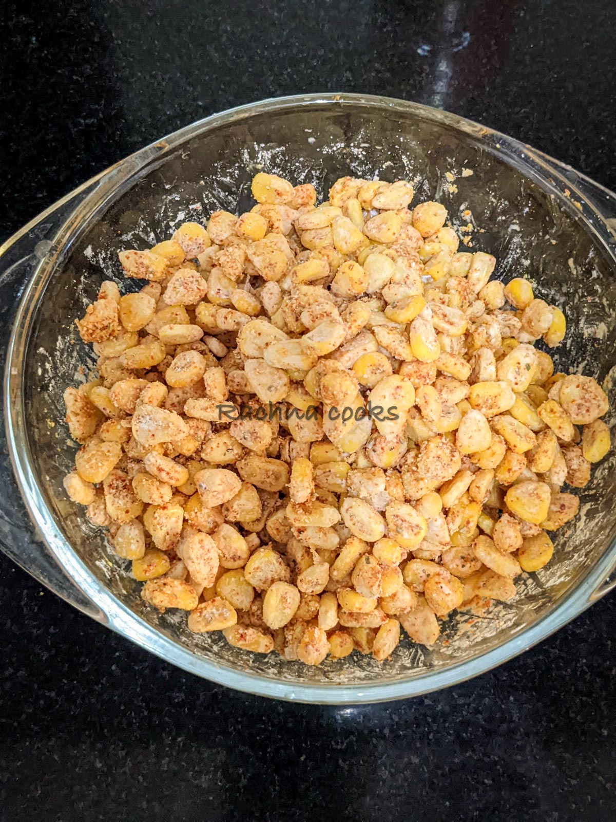 Coated corn after adding lemon juice and oil in a bowl.